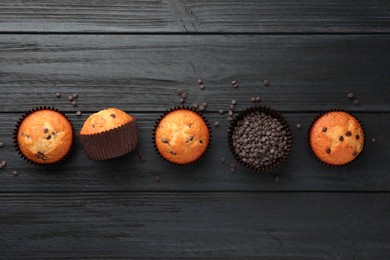 Delicious freshly baked muffins with chocolate chips on dark gray table, flat lay