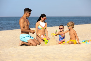 Happy family playing on sandy beach near sea. Summer holidays