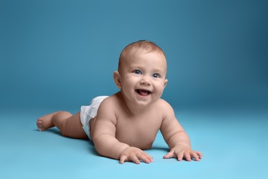 Photo of Cute baby in dry soft diaper lying on light blue background