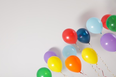 Different bright balloons on light background, space for text. Celebration time