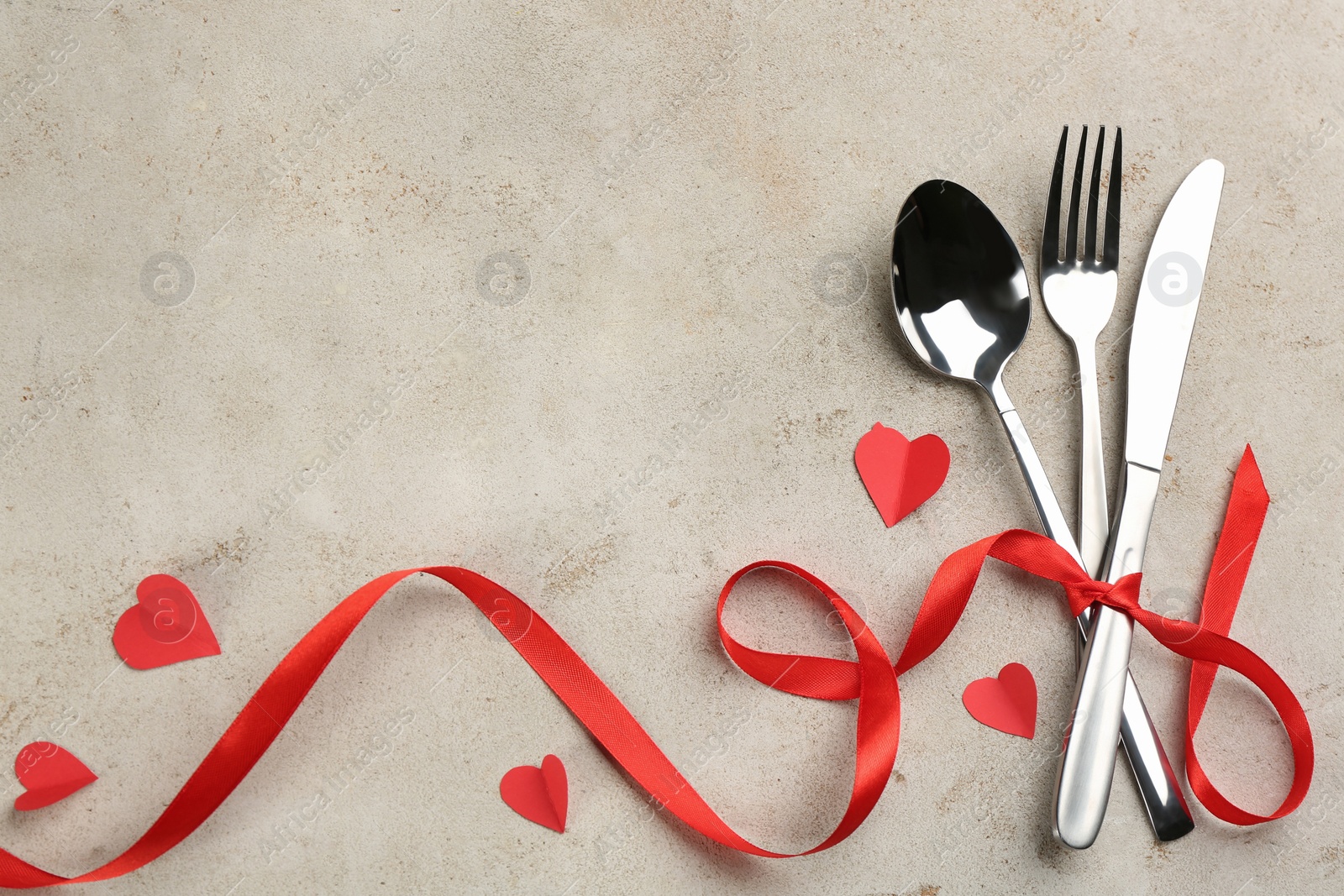 Photo of Cutlery set and red ribbon on light background, flat lay with space for text. Valentine's Day dinner