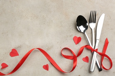 Photo of Cutlery set and red ribbon on light background, flat lay with space for text. Valentine's Day dinner