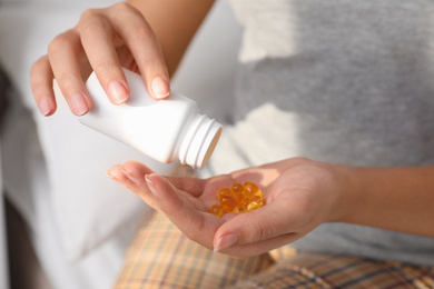 Photo of African-American woman with bottle of vitamin capsules at home, closeup