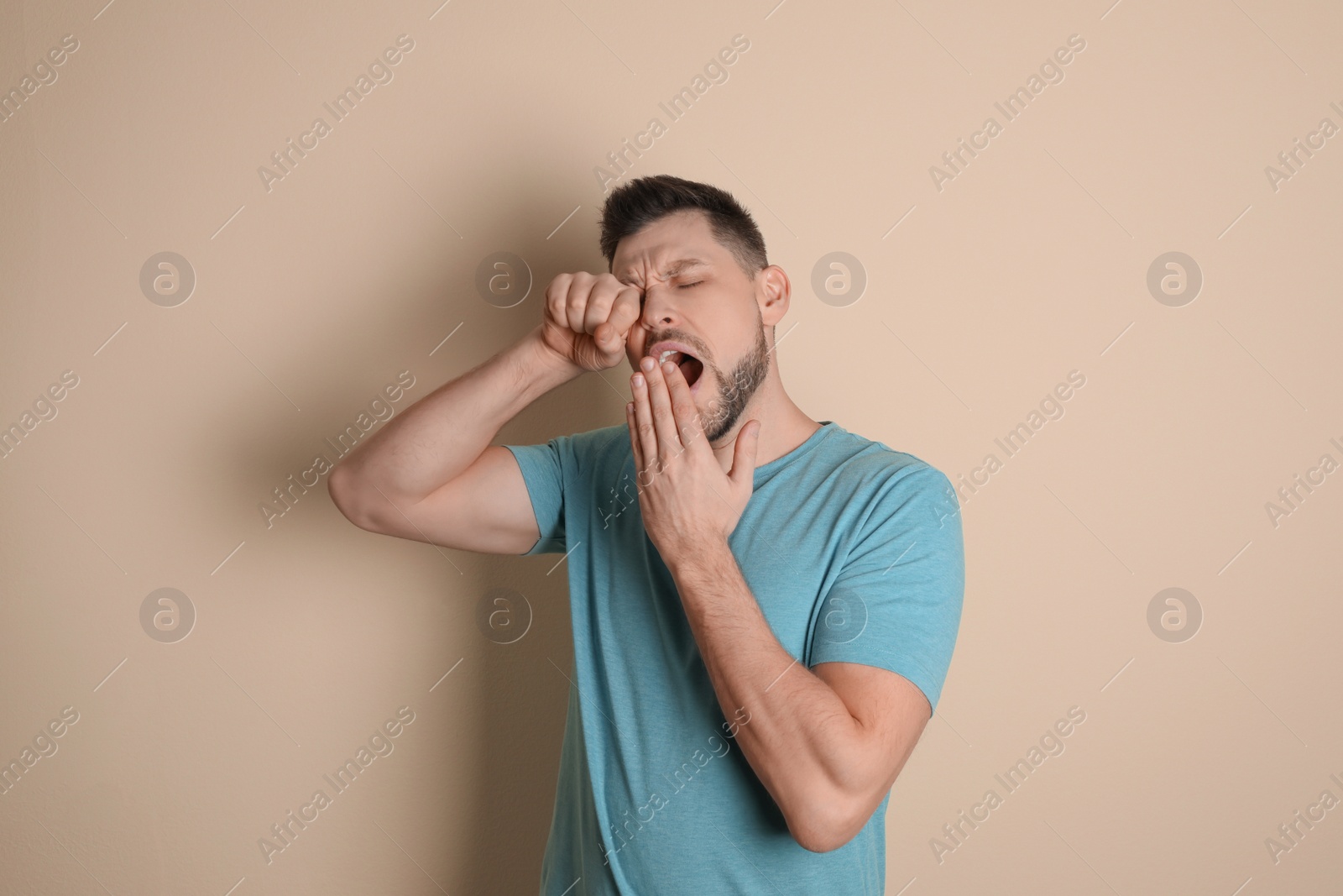 Photo of Portrait of sleepy man yawning on beige background