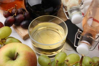 Photo of Different types of vinegar and fresh fruits on table, closeup