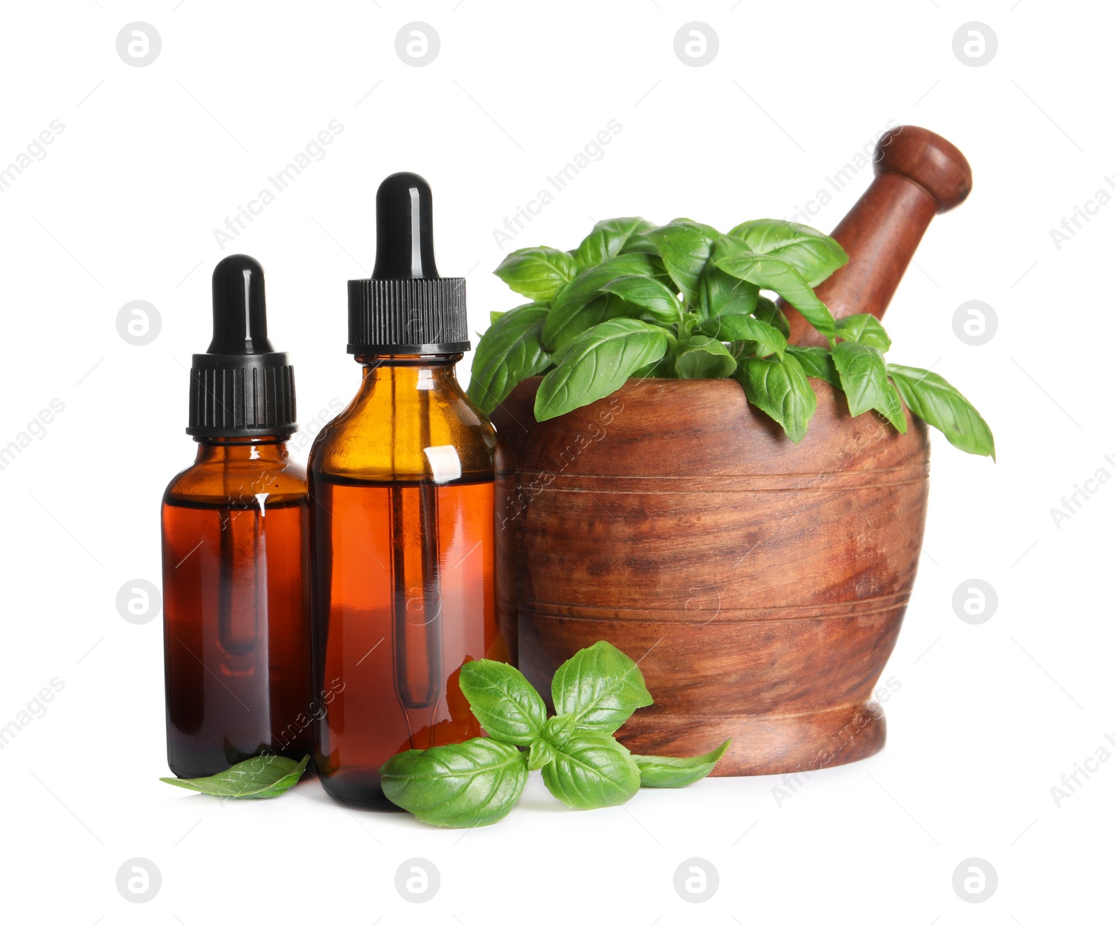 Photo of Bottles of basil essential oil near wooden mortar with leaves and pestle on white background