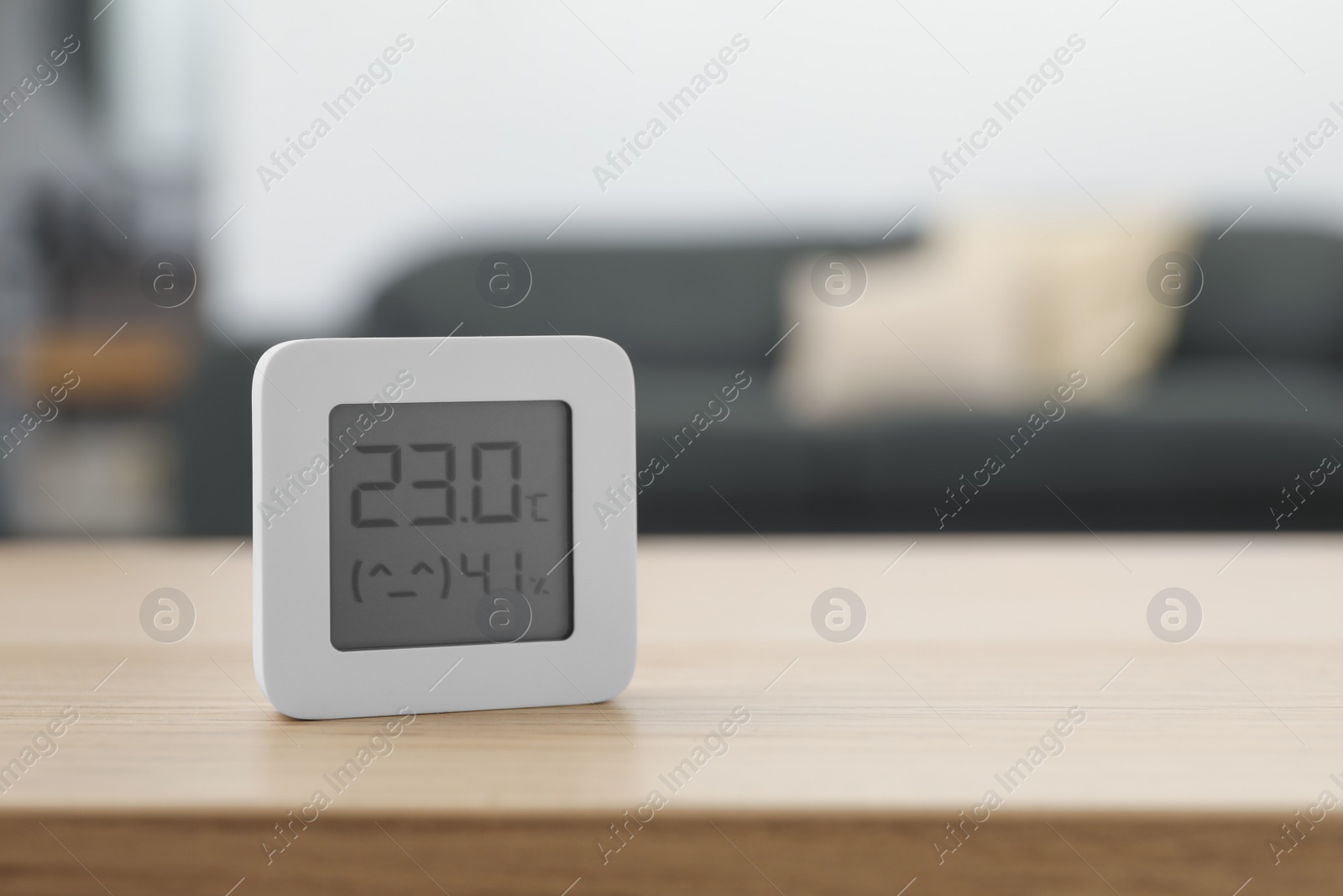 Photo of Digital hygrometer with thermometer on wooden table indoors. Space for text