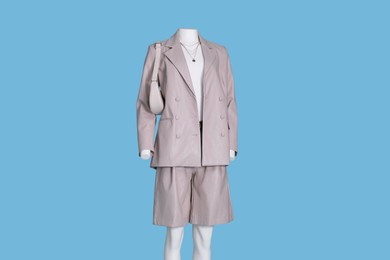 Photo of Female mannequin dressed in white t-shirt and stylish leather suit with accessories on light blue background