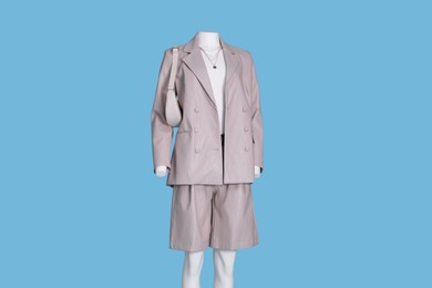 Female mannequin dressed in white t-shirt and stylish leather suit with accessories on light blue background