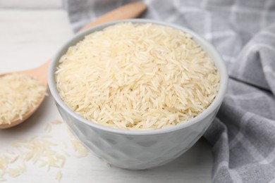 Raw rice in bowl on white table, closeup