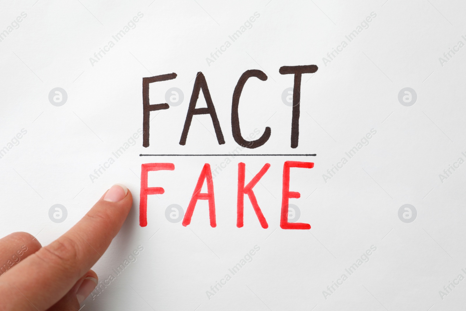 Photo of Woman pointing at words Fact and Fake on white background, top view