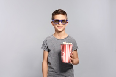 Photo of Boy with 3D glasses and popcorn during cinema show on grey background