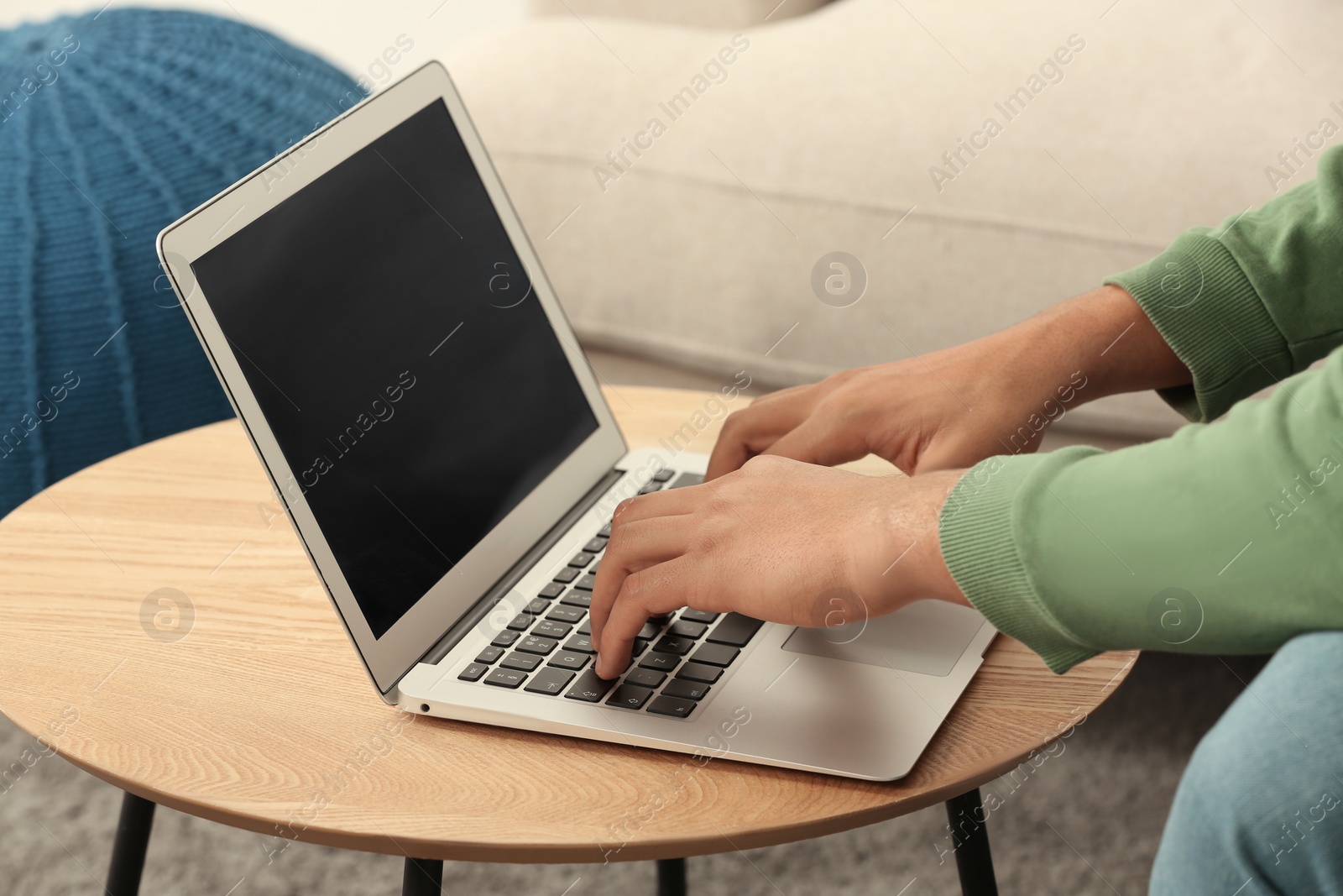 Photo of African American man typing on laptop at table in room, closeup
