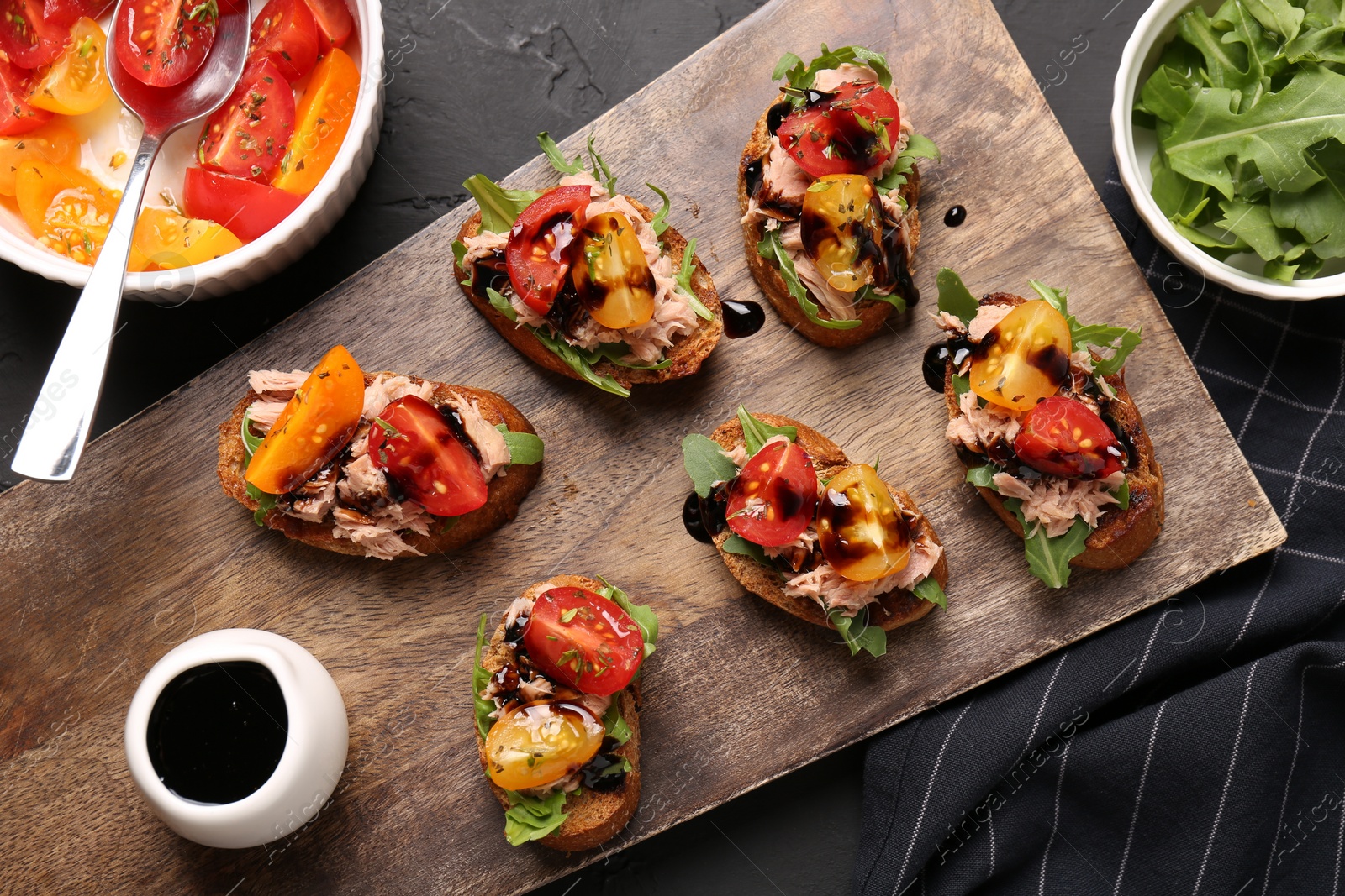 Photo of Delicious bruschettas with balsamic vinegar, tomatoes, arugula and tuna on grey textured table, flat lay