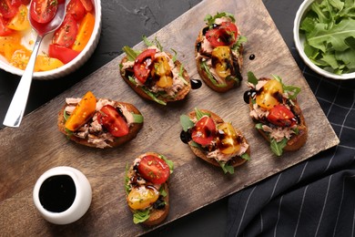 Photo of Delicious bruschettas with balsamic vinegar, tomatoes, arugula and tuna on grey textured table, flat lay