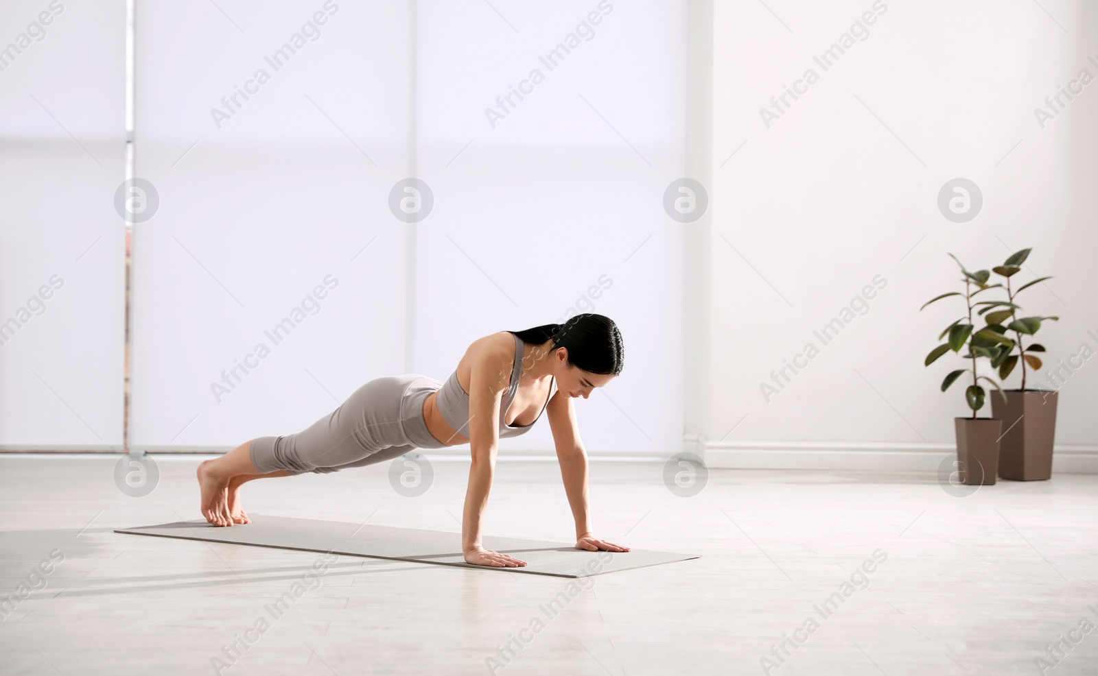 Photo of Young woman practicing plank asana in yoga studio. Phalankasana pose