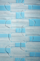 Photo of Disposable face masks on light blue background, flat lay. Protective measures during coronavirus quarantine