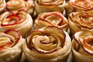 Photo of Freshly baked apple roses on parchment paper, closeup. Beautiful dessert