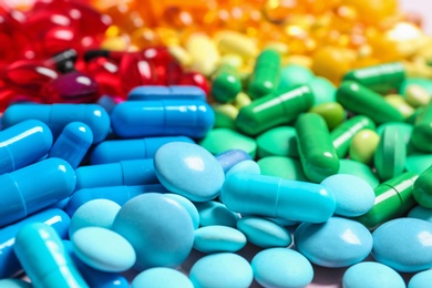 Photo of Heap of different colorful pills on table, closeup