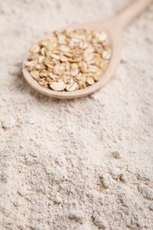 Photo of Spoon with oat flakes on flour, closeup