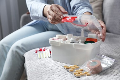 Photo of Woman opening first aid kit indoors, closeup