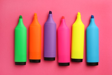 Photo of Bright color markers on pink background, flat lay