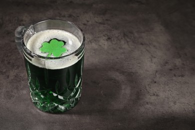 Photo of St. Patrick's day celebration. Green beer with decorative clover leaf on grey table. Space for text