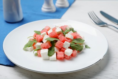 Photo of Delicious salad with watermelon, arugula and feta cheese served on white wooden table