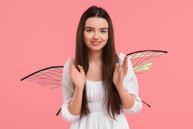 Photo of Beautiful girl in fairy costume with wings on pink background