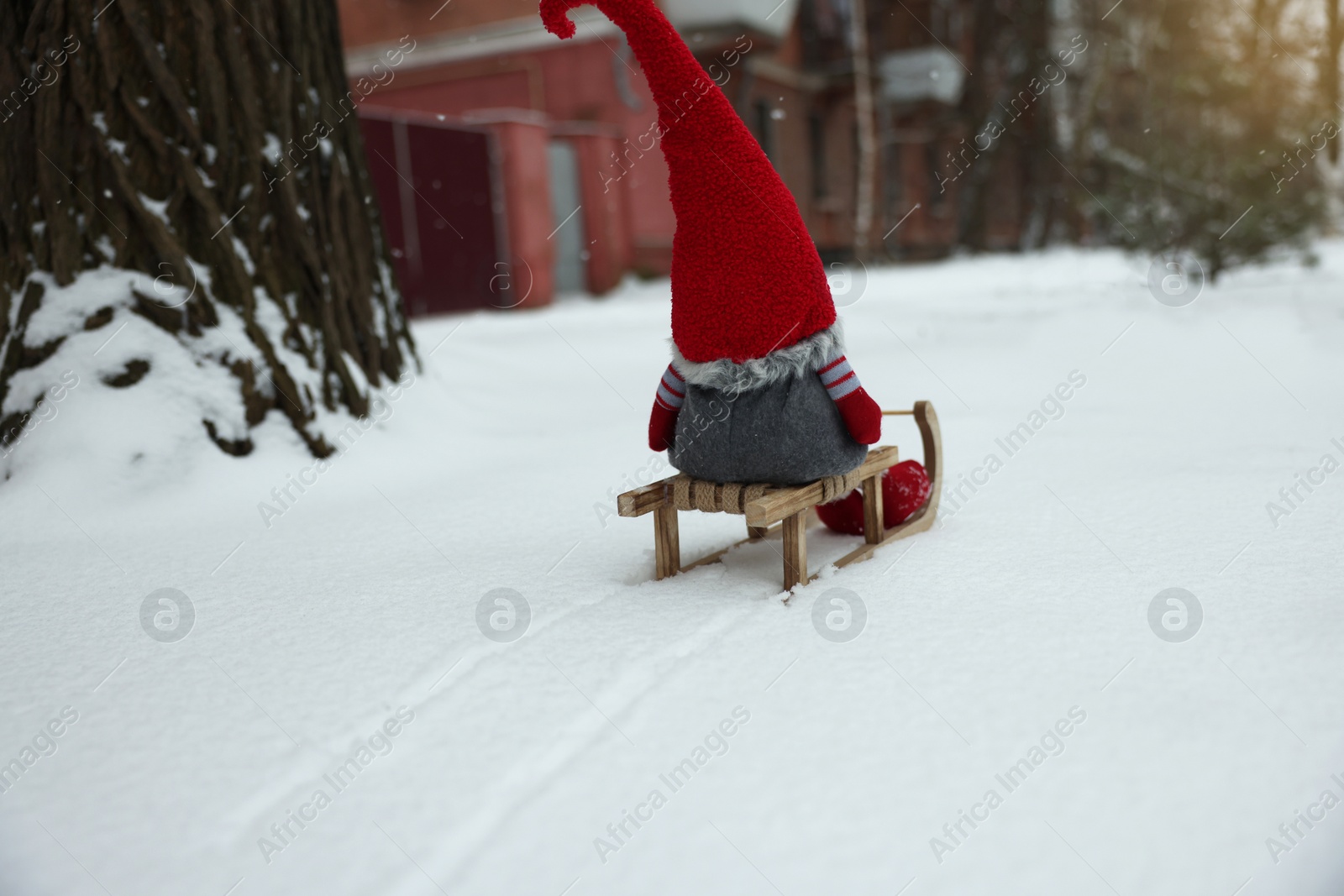 Photo of Wooden sleigh with Christmas gnome on snow outdoors