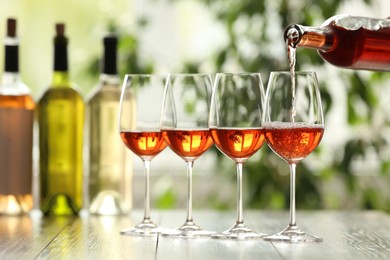 Photo of Pouring white wine from bottle into glass on wooden table
