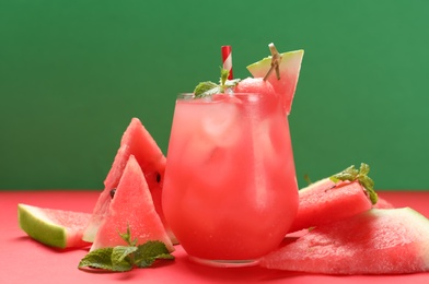 Photo of Tasty watermelon drink and fresh fruits on red table against green background