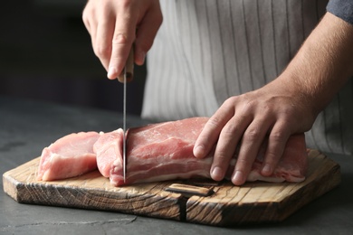 Photo of Man cutting fresh raw meat on table, closeup