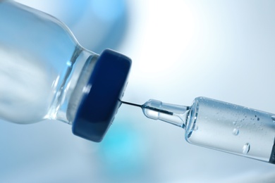 Photo of Filling syringe with COVID-19 vaccine on blurred background, closeup