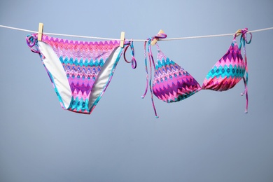 Photo of Stylish bikini hanging on rope against color background