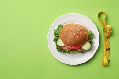 Photo of Plate with tasty sandwich and measuring tape on color background, top view. Healthy diet