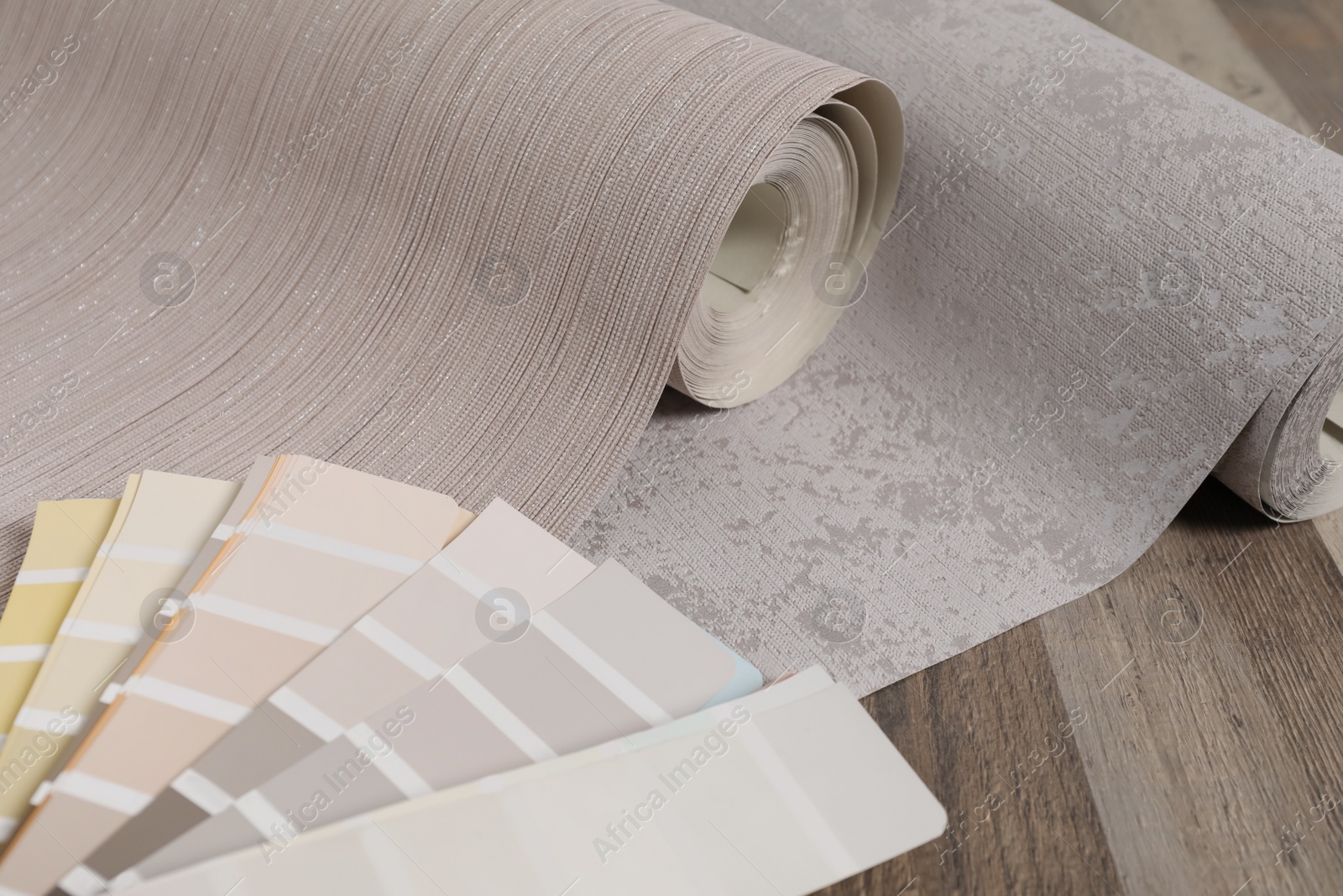 Photo of Wall paper rolls and color palette on wooden floor