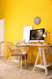 Photo of Stylish home office interior with comfortable workplace near yellow brick wall