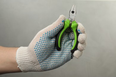 Photo of Man with combination pliers on grey background, closeup