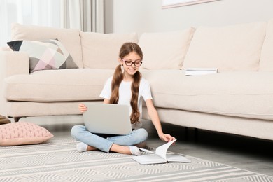 Photo of Girl with laptop and book sitting on floor at home