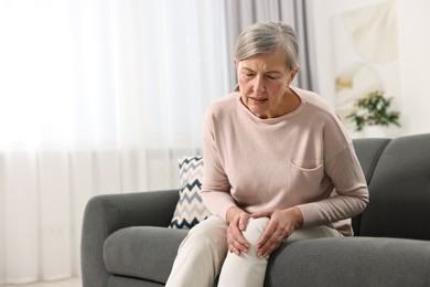 Photo of Arthritis symptoms. Woman suffering from pain in knee at home