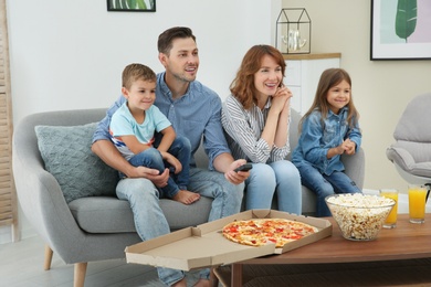 Family watching TV in room at home