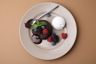 Photo of Delicious chocolate fondant served with fresh berries and ice cream on beige background, top view