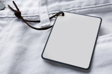 Photo of Cardboard tag with space for text on white jeans, closeup