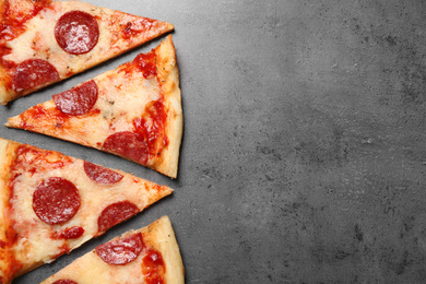 Slices of hot delicious pepperoni pizza on grey table, flat lay. Space for text