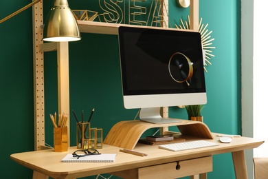 Photo of Stylish room interior with modern workplace at color wall