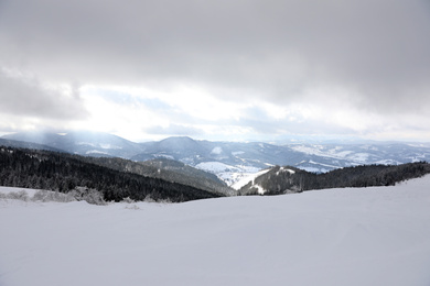 Photo of Picturesque mountain landscape with snowy hills under cloudy sky