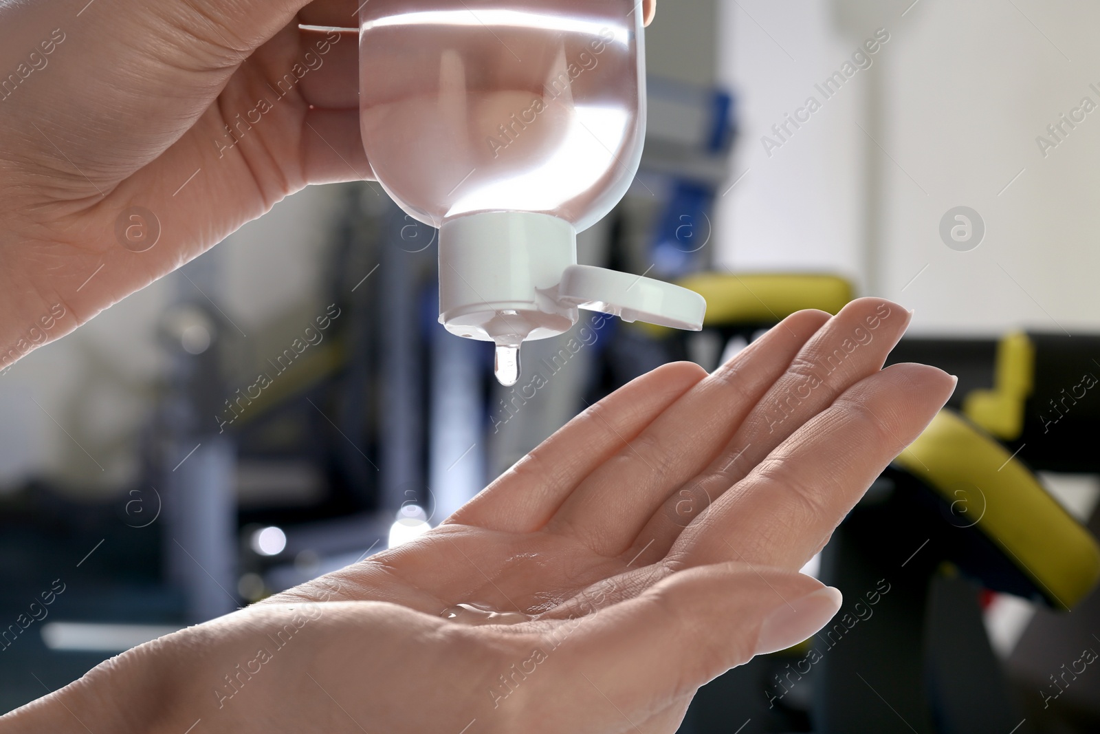 Image of Woman applying antiseptic gel at gym, closeup. Preventive measures during epidemic period 