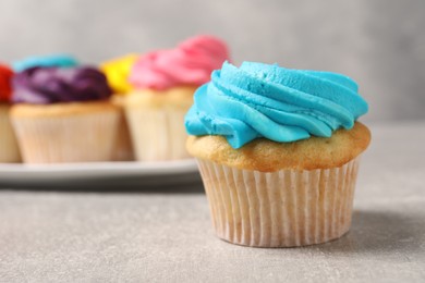 Photo of Delicious cupcakes with bright cream on gray table, selective focus