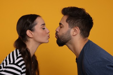 Photo of Cute young couple kissing on orange background
